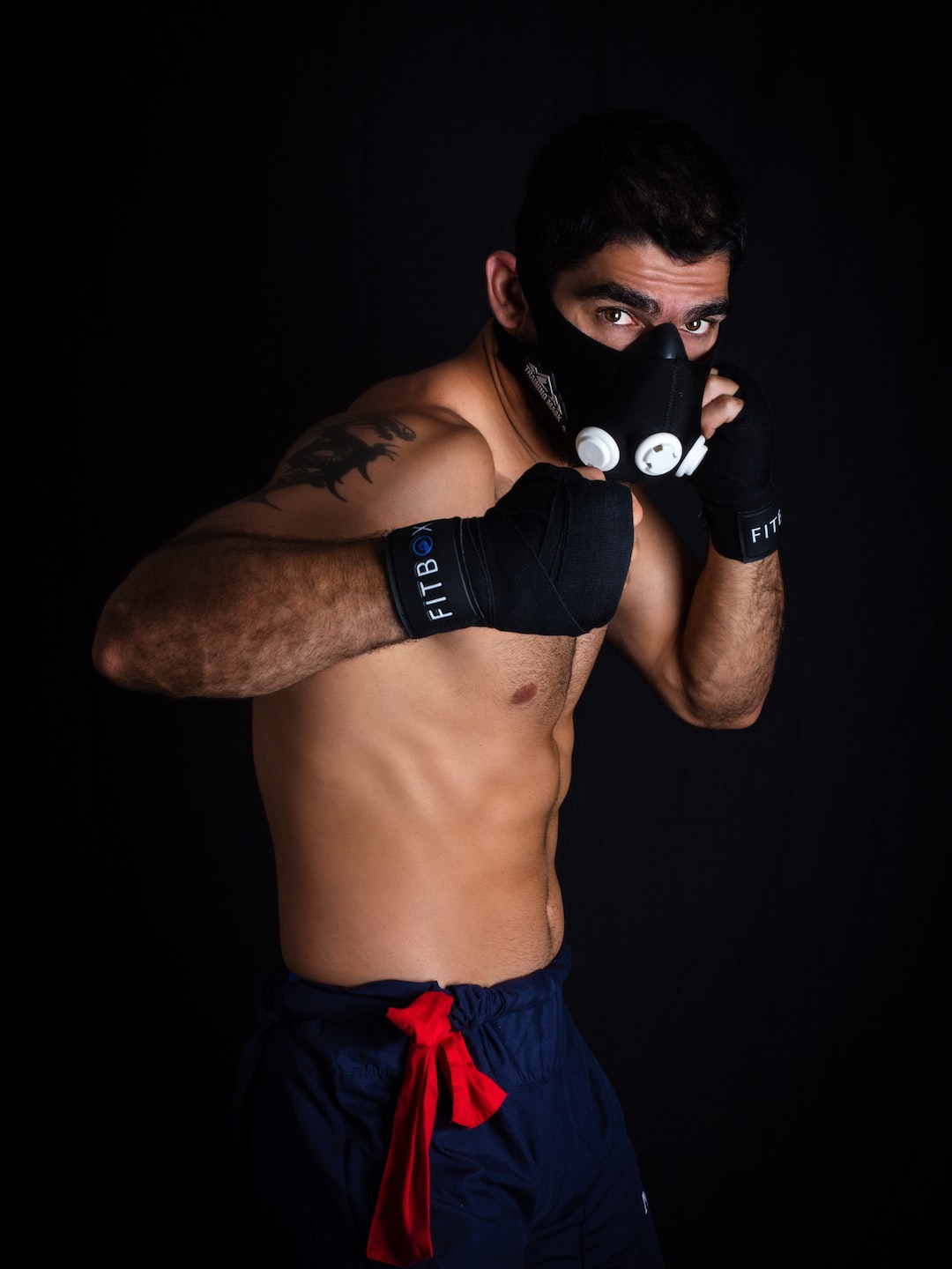 topless man wearing black boxing gloves