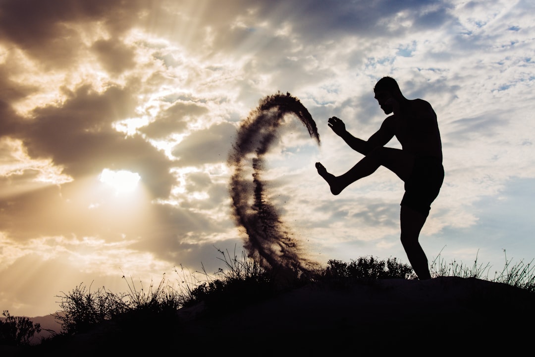 Man fighting with shadow by MMA Ninja a man standing on top of a grass covered hill