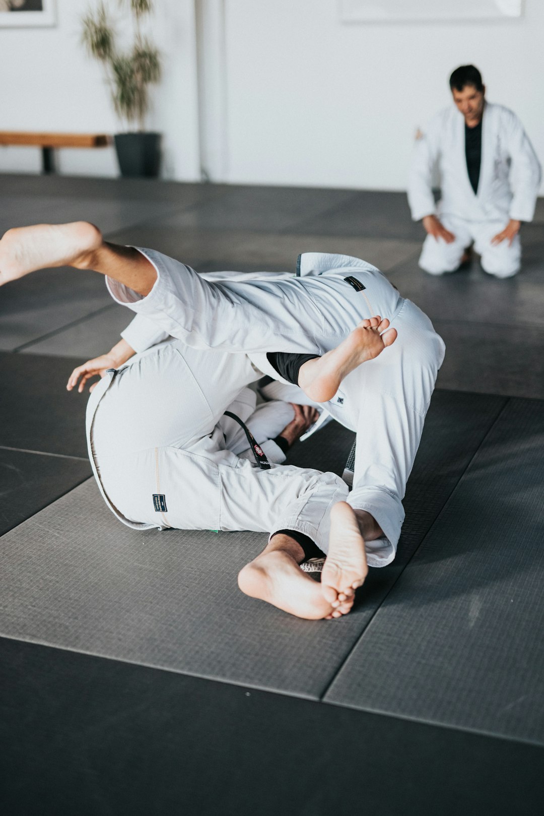 Conclusion by MMA Ninja man in white t-shirt and white pants lying on black floor