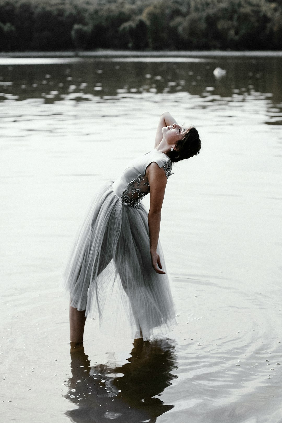 Dreamy girl by MMA Ninja woman in gray dress standing on shallow body of water